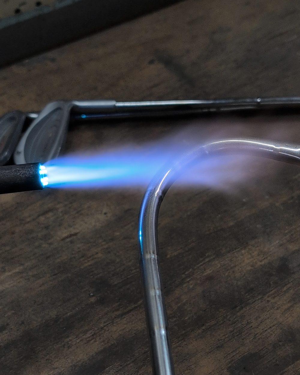 A torch heating the steel shaft of a golf iron at the bend